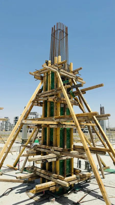 A column in its formwork, braced with timber props, against a blue sky