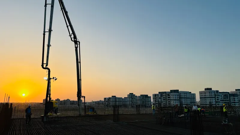 A concrete pump boom over the reinforced deck at sunset